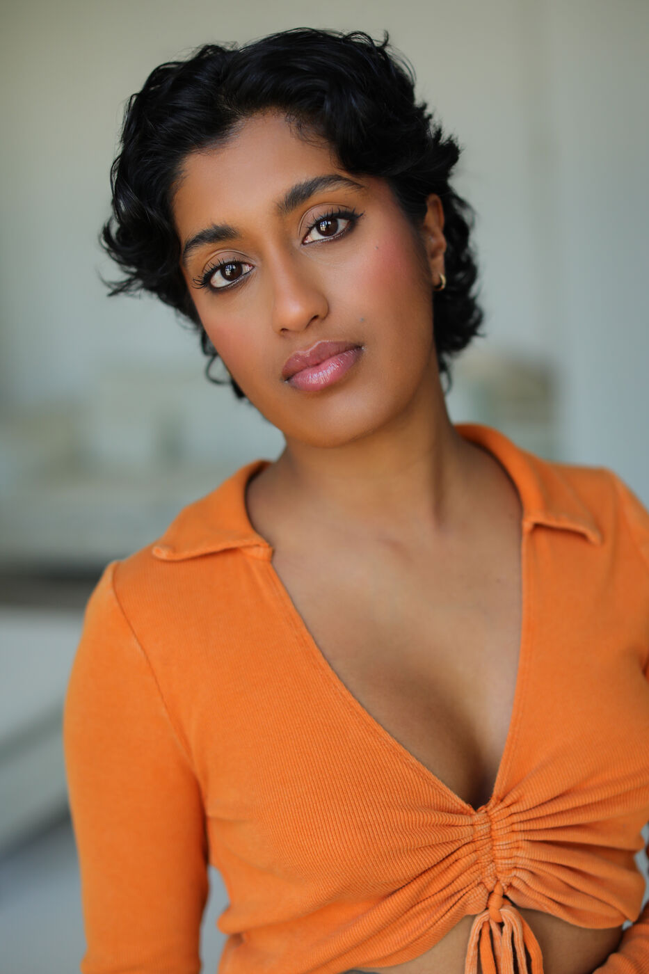 Headshot of Uma Paranjpe — orange top, soft natural light