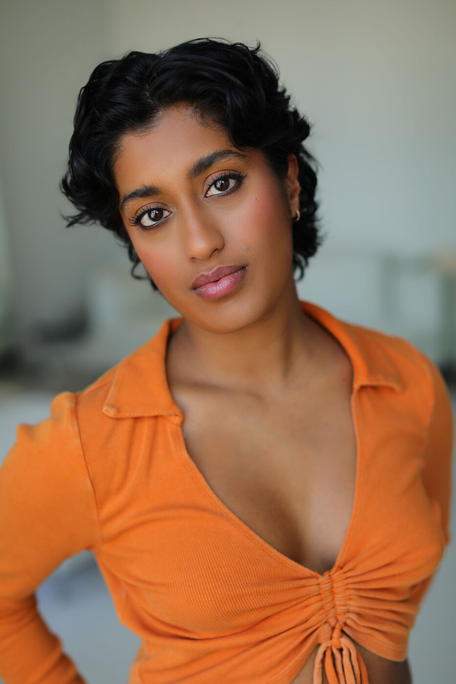 Headshot of Uma Paranjpe — head tilt in orange top