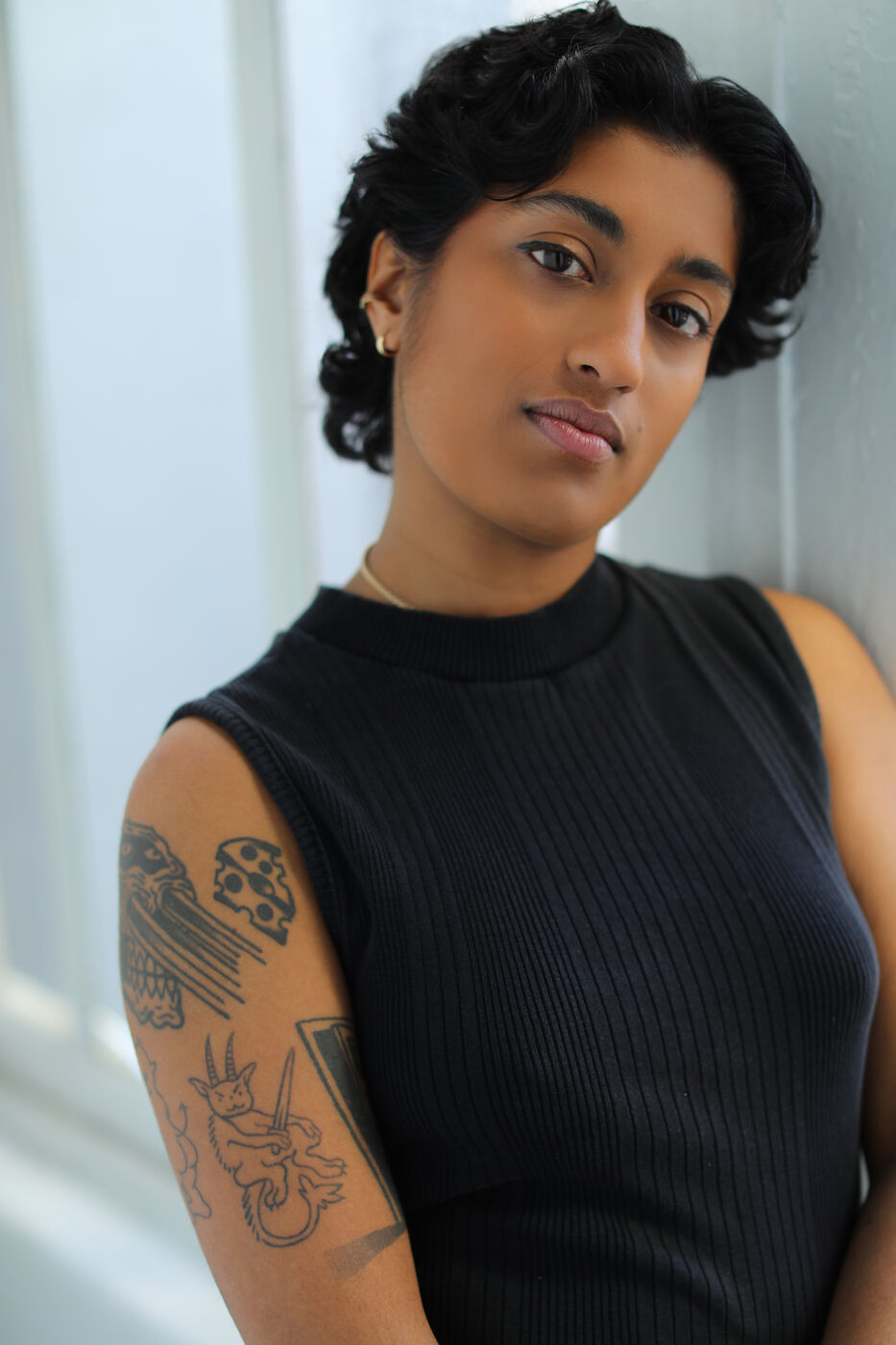 Headshot of Uma Paranjpe — black tank, leaning against wall