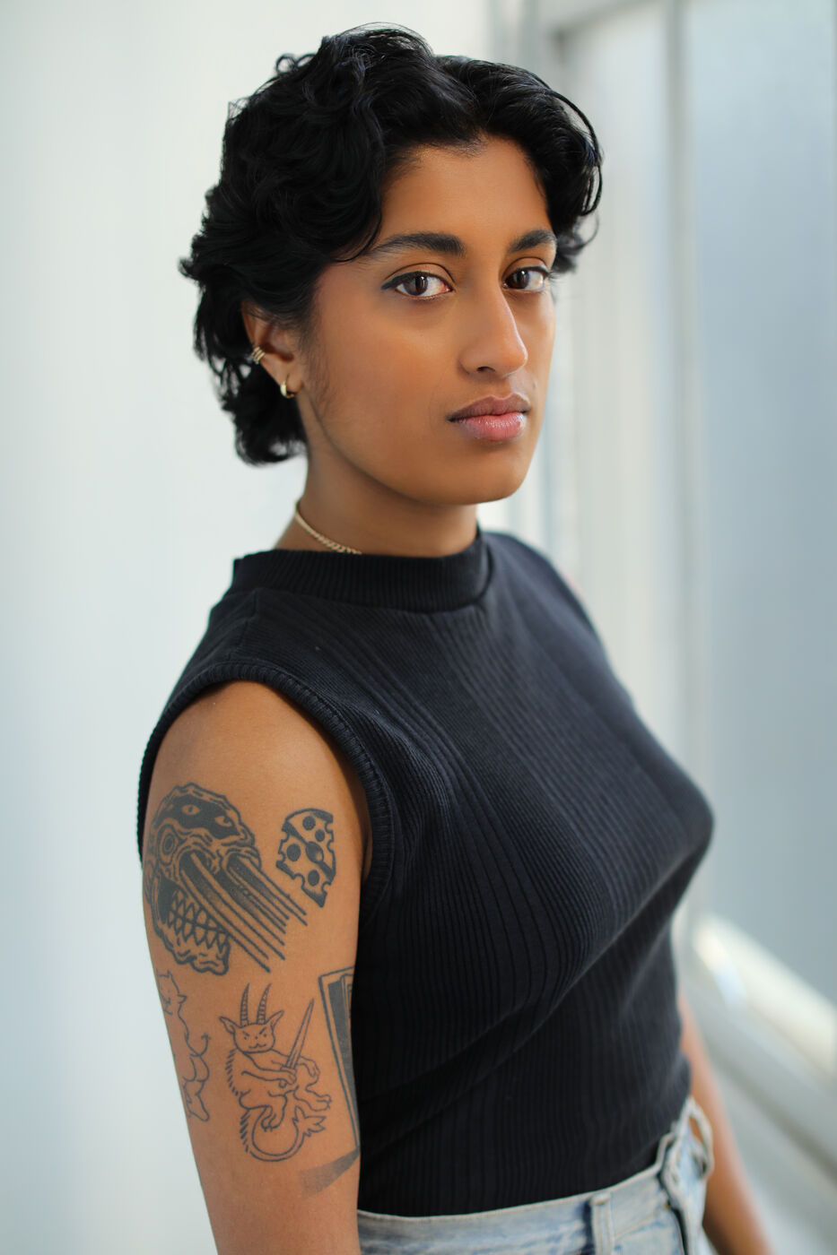 Headshot of Uma Paranjpe — black tank by window, side gaze