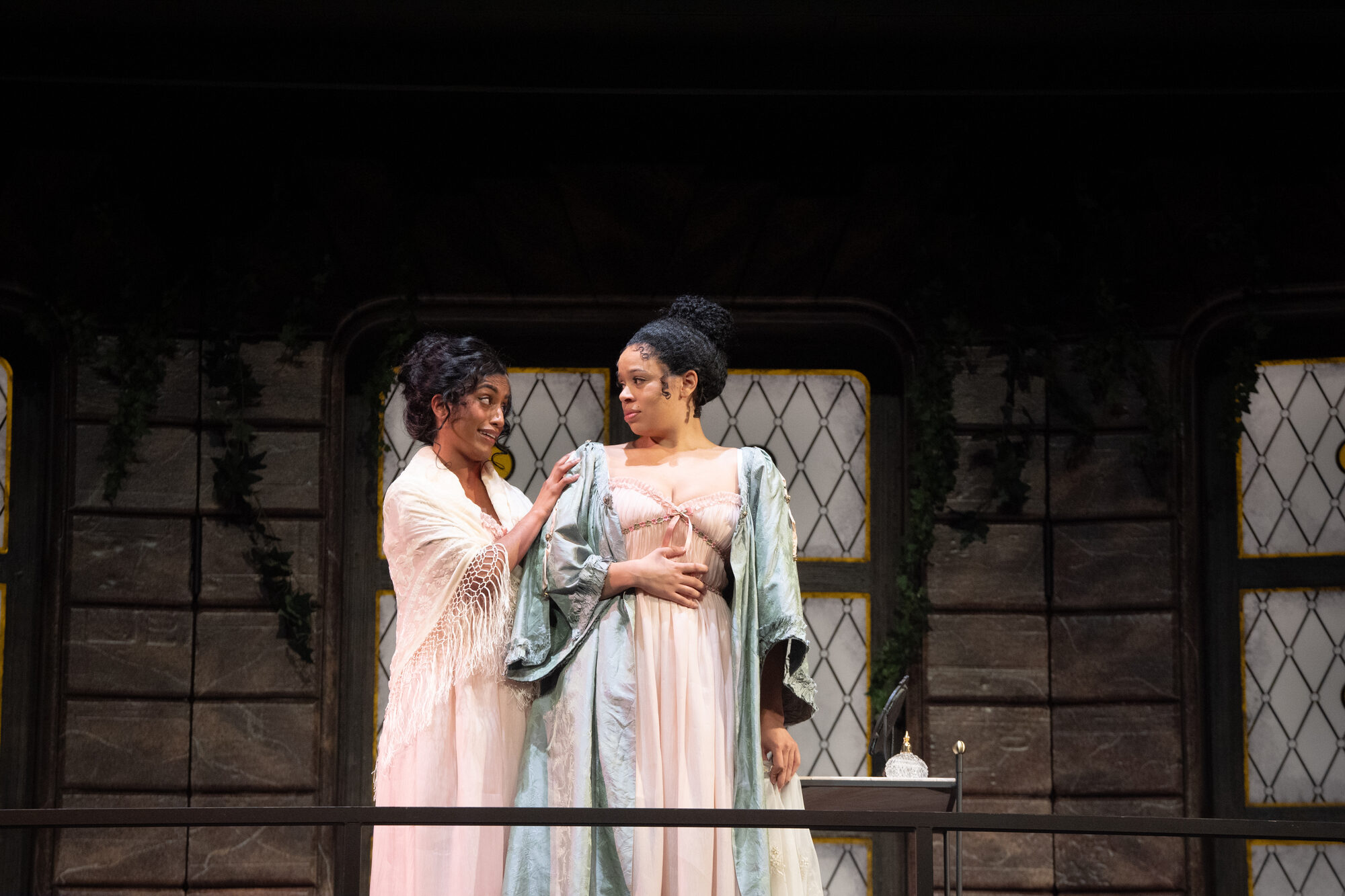 Two actors in regency-era costumes on a balcony