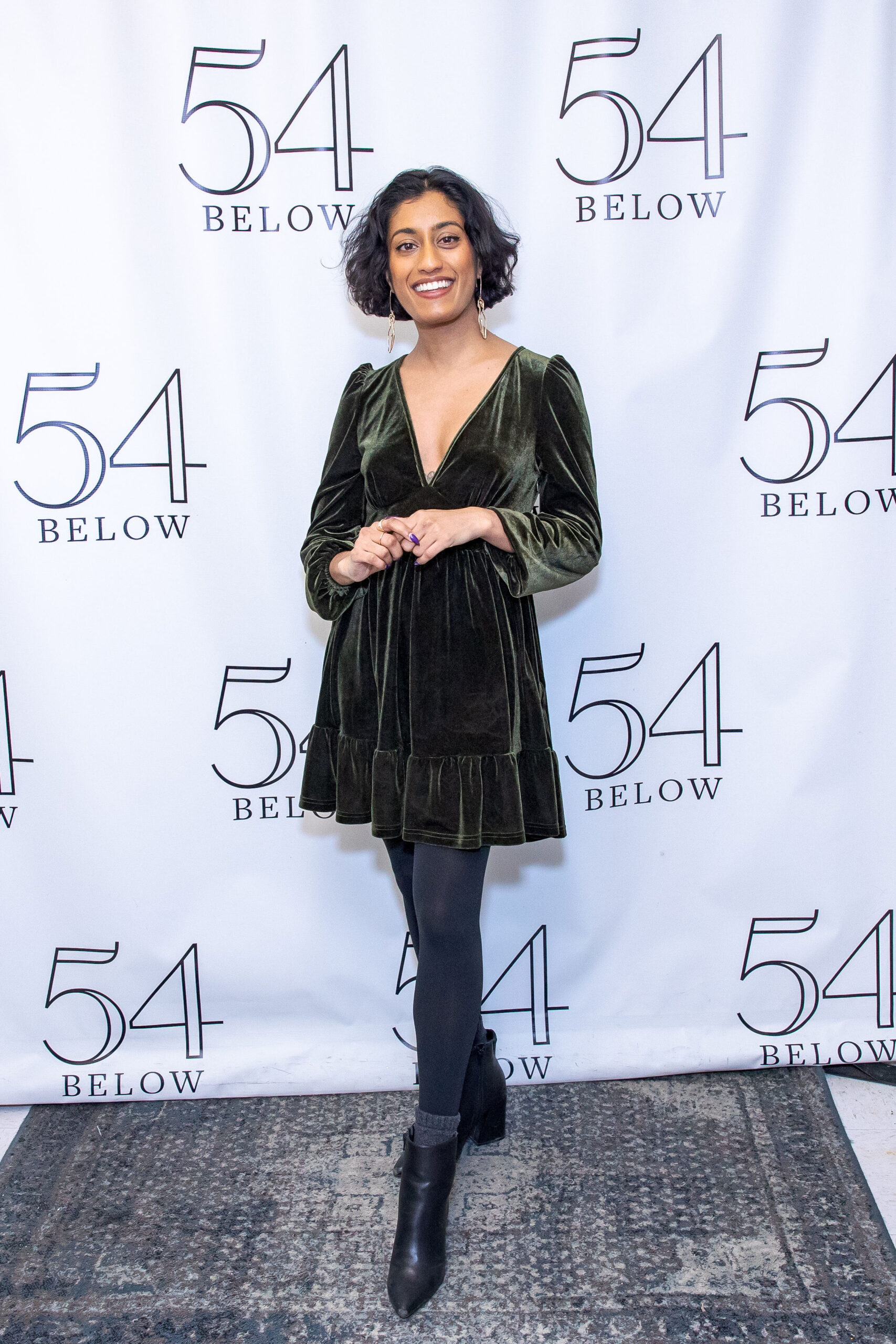 Uma in front of a step and repeat for 54 Below